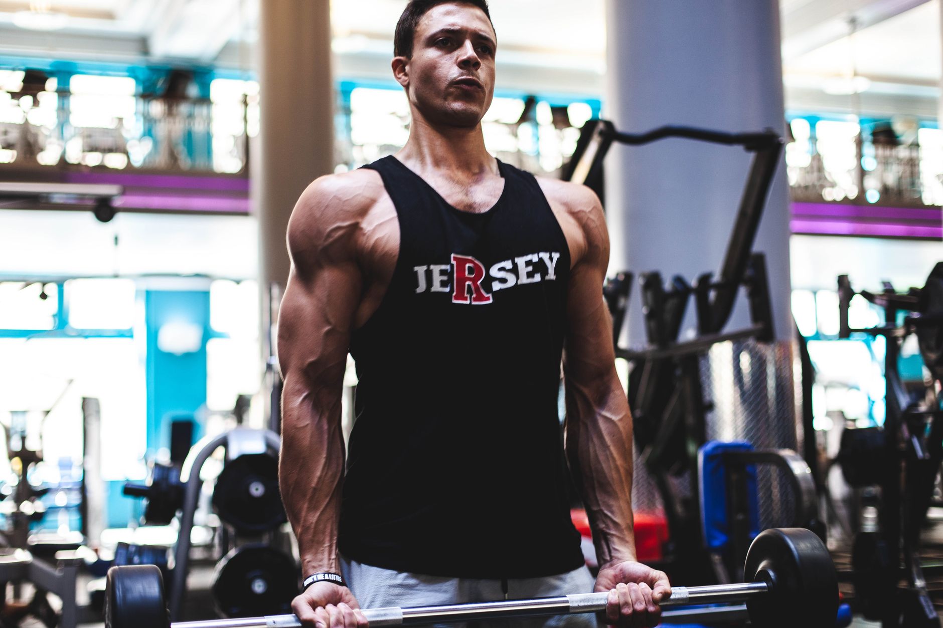 Fit man in a gym lifting barbell, showcasing strength and fitness in activewear. — Elevate Your Workout Routine with UK Fitne